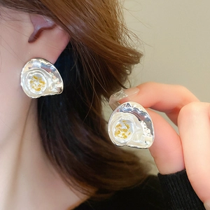Détail de boucles d'oreilles argentées en nacre synthétique et feuilles d'or