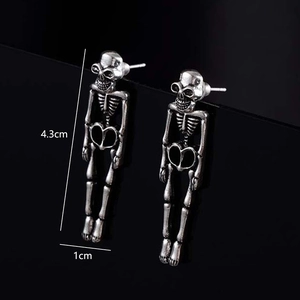 Gothic silver skull skeleton drop earrings for women on a dark reflective surface