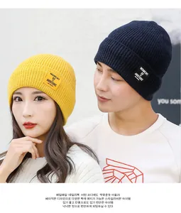 Detail of ribbed knit beanies in navy and yellow with Moment of Ambitions woven patches