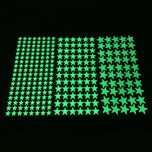Luminous green star wall stickers in multiple sizes glowing against a dark background