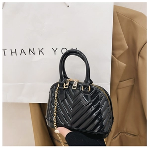 Detail of black glossy jelly shell bag featuring V-shaped quilting and gold chain strap