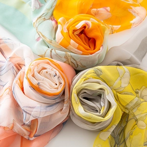 Detail of four floral silk scarves rolled into rose shapes in various vibrant colors