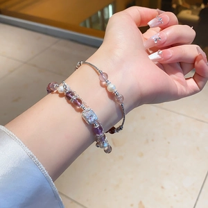 Detailed macro view of layered amethyst and pearl bracelets on a model wrist