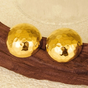 Gros plan de boucles d'oreilles dorées bombées avec texture martelée sur socle en bois