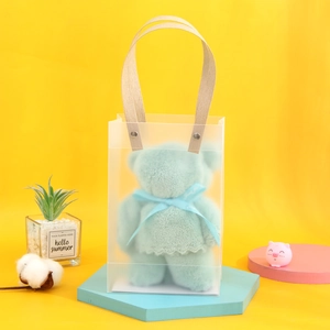 Detail of mint green bear towel in frosted PVC gift bag with wooden handle