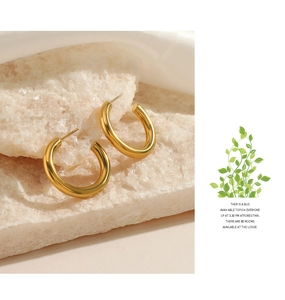 Macro detail of chunky gold hoop earrings placed on a textured white stone surface
