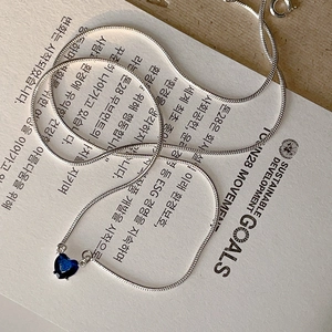 Detail of silver snake chain necklace with deep blue heart-shaped zircon pendant