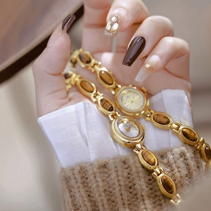 Detail of gold vintage watch with oval tiger eye stone links on model's wrist