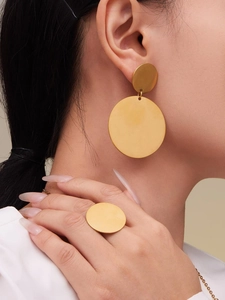 Gros plan d'un modèle portant un ensemble boucles d'oreilles et bague dorées en acier
