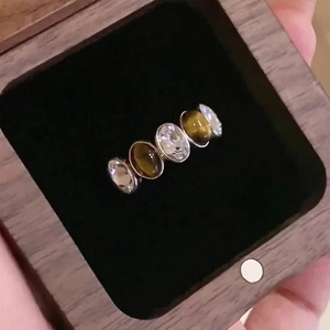 Top view of five-stone ring with tiger eye and zircons in a wooden jewelry box