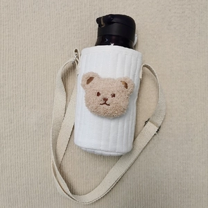 Top view of white quilted fabric water bottle holder with plush bear and adjustable strap