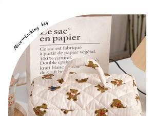 Detail of quilted cosmetic bag with cute brown bear print and striped handles