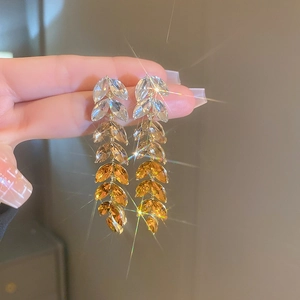 Macro detail of long gradient tassel earrings featuring marquise-cut amber crystals