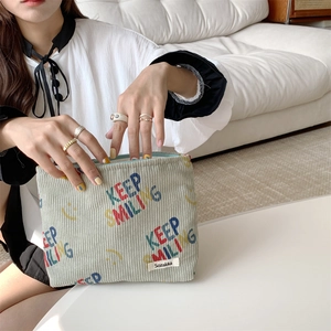Detail view of corduroy makeup bag featuring KEEP SMILING print and zipper closure