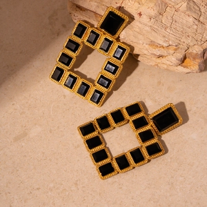 Détail de boucles d'oreilles dorées vintage avec pierres carrées noires incrustées