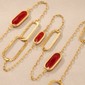 Zweilagige Goldkette mit geometrischem rotem Glasstein und gehämmerten Metallanhängern