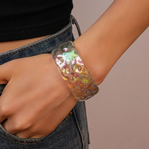 Close-up of an iridescent acrylic wide bangle featuring a unique wave texture on the wrist