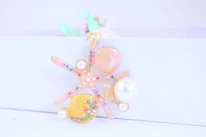 Detail of starfish and shell charm with pink enamel, faux pearls, and sparkling crystals