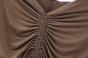 Detailed close-up of brown knitted fabric texture with central ruched pleat design