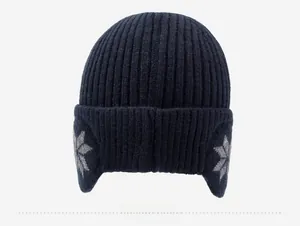 Detail of dark blue knitted winter hat with ear flaps and gray snowflake pattern texture
