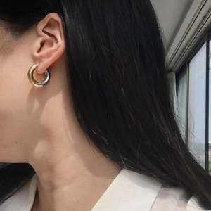 Minimalist thick two-tone gold and silver spliced stainless steel hoop earring on a model