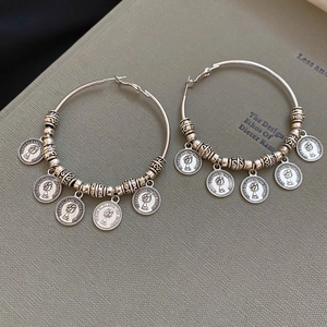 Detail of silver geometric hoop earrings with portrait coin pendants and vintage finish