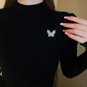 Detail of a sparkling crystal butterfly brooch pinned on a black long-sleeved dress