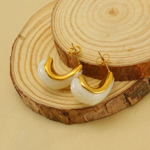 Modern gold-plated stainless steel teardrop earrings with milky white resin on wood