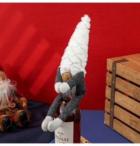 Detail of Christmas gnome wine bottle cover with plush white hat and grey body