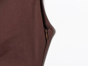 Details von hochdichtem Stoff und einem verdeckten Reißverschluss am dunkelbraunen Kleid