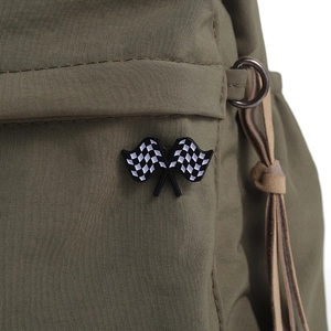Green fabric bag detail with iconic black and white checkered racing flag enamel brooch