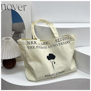 Detail of canvas tote bag with black floral print and NKK ART STUDIO typography design