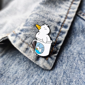 Cute white enamel duck pin brooch in a coffee cup sleeping shown on denim fabric