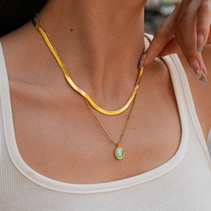 Détail d'un collier doré à deux rangs avec pendentif ovale vert sur mannequin