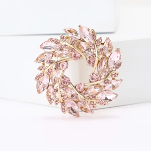 Macro shot of circular wheat wreath brooch with pink crystals and gold-tone finish