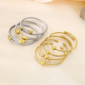 Close-up of twisted steel cable bangles in gold and silver finish with metal beads