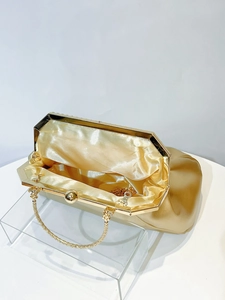 Detail view of gold evening bag showing luxury silk lining and golden spherical clasp