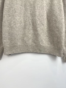 Detailed macro view of the soft beige knit texture and ribbed hem on the cardigan
