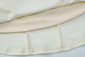 Detailansicht der hochwertigen Overlock-Naht am Saum des weißen plissierten Kleides