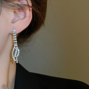 Macro shot of silver leaf-shaped earrings with sparkling diamonds on a model