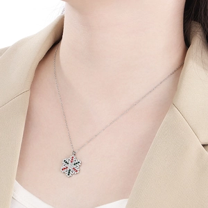 Detailed view of silver snowflake pendant necklace with festive red and green zircons