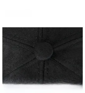 Close-up of the top button and reinforced stitching on a black twill cotton baseball cap