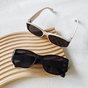 Polarized black and beige sunglasses displayed on a stylish wave-shaped wooden tray