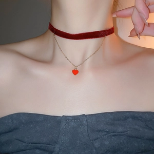 Detail of red velvet choker with gold chain and heart pendant on a model