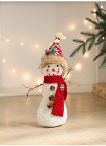 Detailed view of plush Christmas snowman ornament with red scarf on wood floor