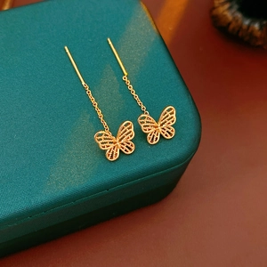 Macro view of gold butterfly threader earrings featuring delicate hollow metal wings