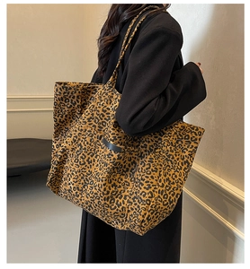 Détail du sac cabas en toile léopard avec poche en cuir noir et fines bandoulières