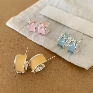 Detailed close-up of sweet colorful enamel bow stud earrings in pink blue and yellow
