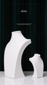 Close-up of white leather necklace bust stands on marble base with green velvet background