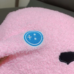 Close-up of pink sherpa fleece texture with a cute blue and white smiley face embroidery